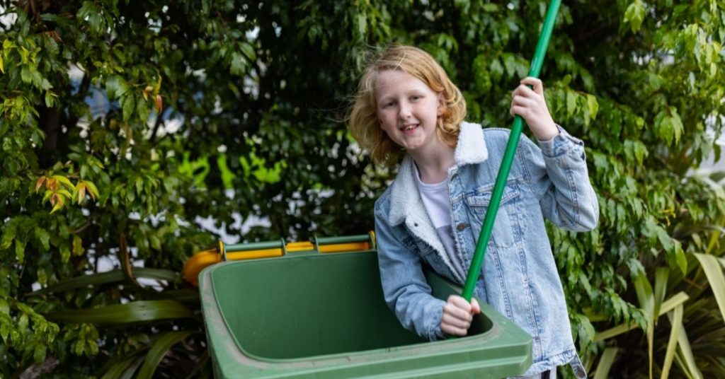 crutis cleaning the inside of a green wheelie bin